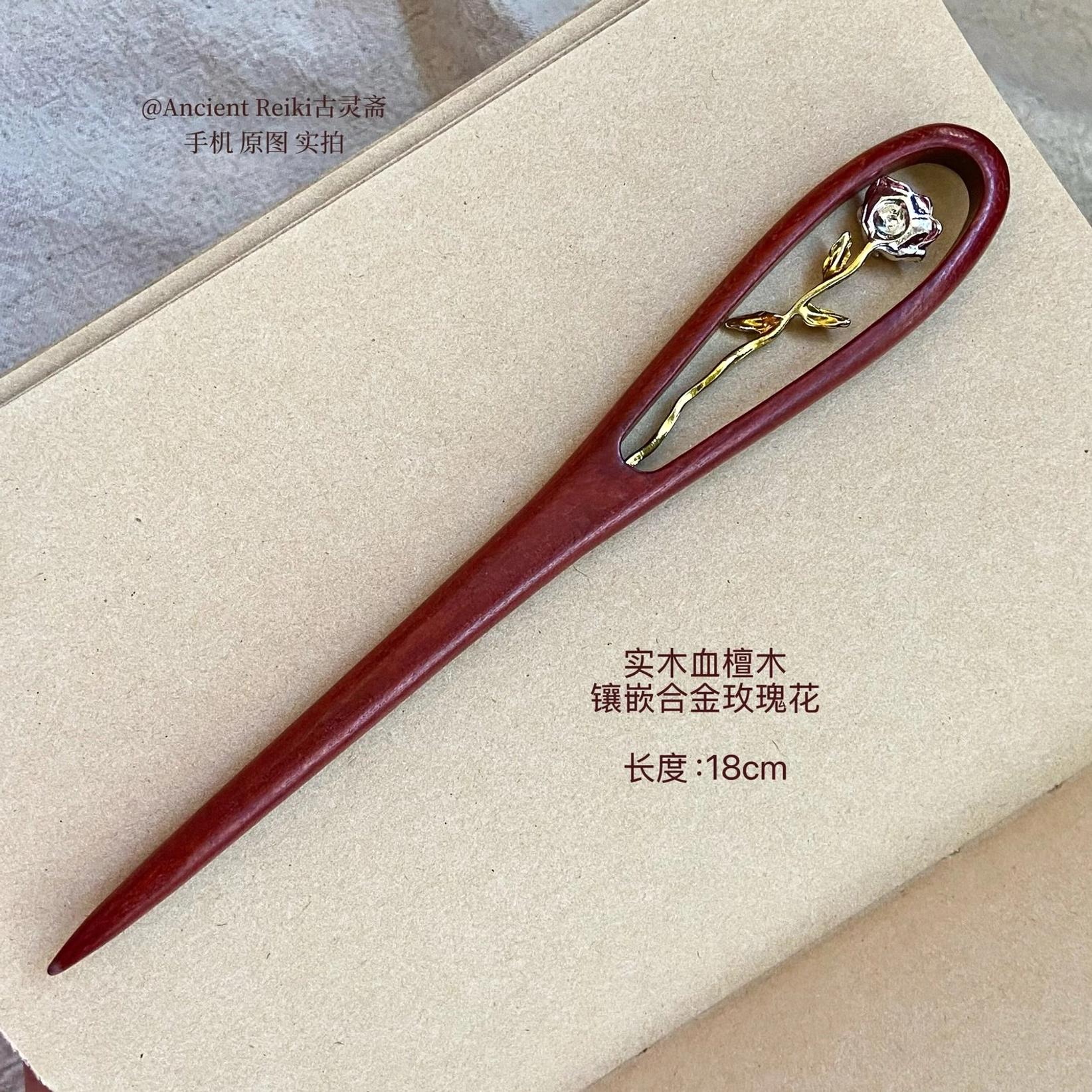 18cm blood sandalwood Chinese hairpin with alloy rose decoration shown on a vintage notebook for traditional hanfu hair styling