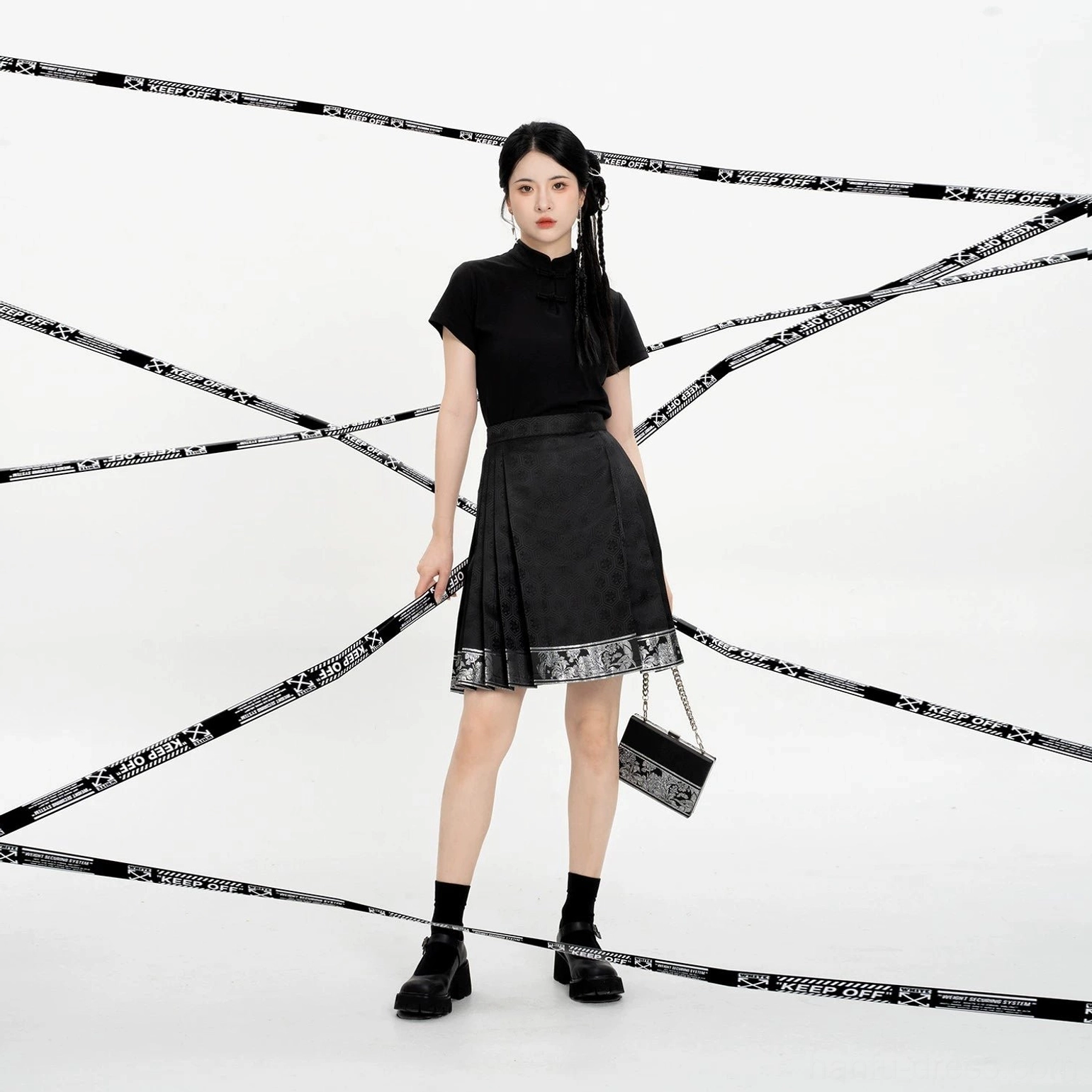 Front view of an all-black Chinese-style outfit featuring a Ming-inspired mini mamian skirt, platform shoes, socks, and a chain crossbody bag