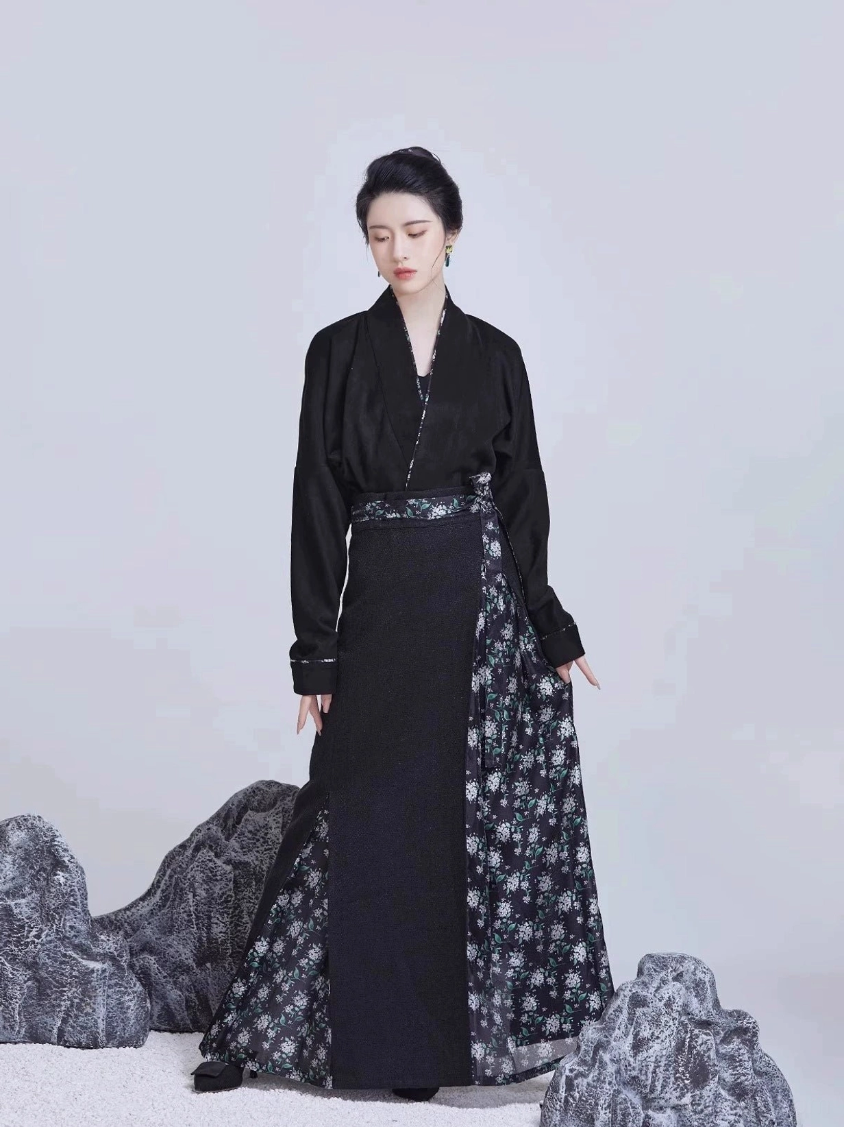 All-black Song Dynasty modern Hanfu outfit with cross-collar top, black pleated skirt, floral side panel, and decorative waist sash shown from the front
