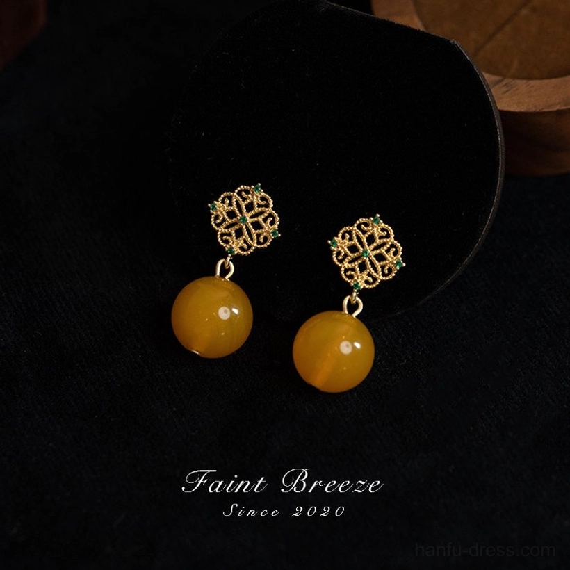 Front view of amber-colored bead dangle Chinese earrings with gold flower ear tops, green gemstone accents, and an elegant traditional floral jewelry design