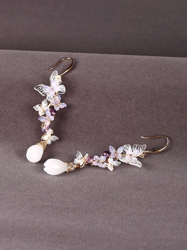 Full pair of amethyst butterfly drop Chinese earrings laid flat on dark fabric, clearly showing the matching purple bead and teardrop design