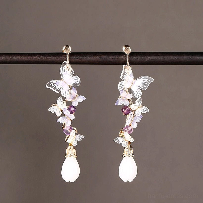Amethyst butterfly drop Chinese earrings displayed from the front with translucent purple butterflies, clustered violet beads, white teardrop pendants and gold-tone ear wires