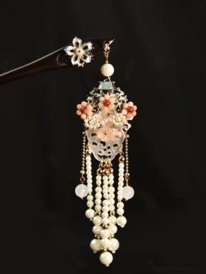 Ancient Chinese style tassel hairpin with dark wooden hair stick, blue enamel flower, pink floral pendant, translucent carved jade-inspired charm, layered pearl tassels, and gold-tone chains on black background