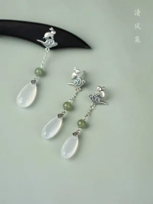 Pair of antique Chinese jade dangle earrings displayed from above with green jade beads, retro silver-toned metalwork, and elegant white teardrop charms
