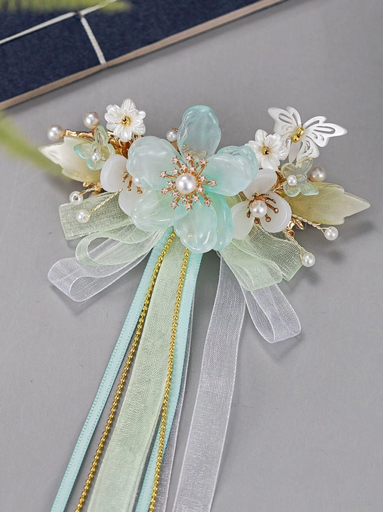 Close-up of antique Chinese style mint green Hanfu back hairpin with layered organza bow gold accents floral details and long flowing tassels