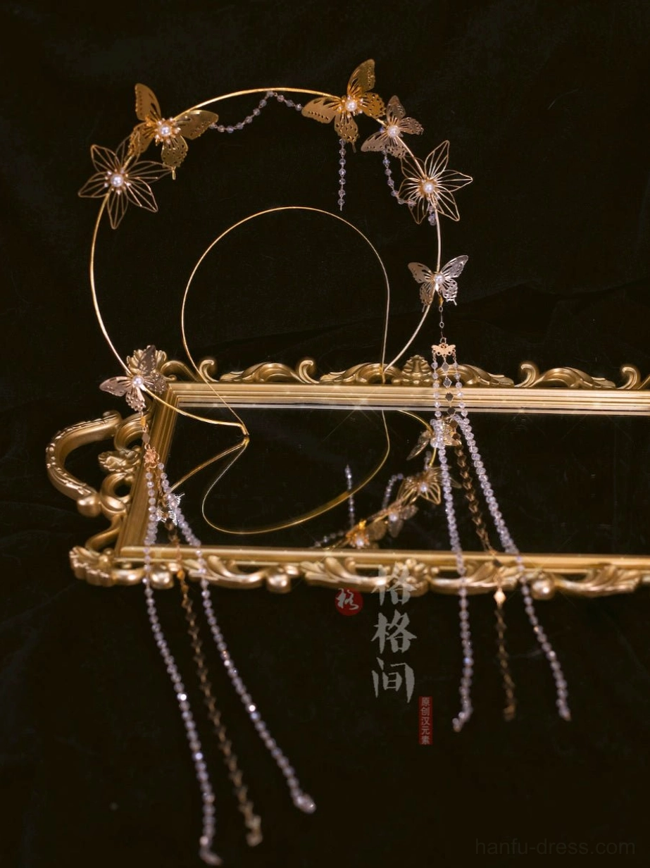 Antique gold-tone Hanfu halo hairband with hollow butterfly ornaments and hanging beaded tassels displayed on a vintage golden frame
