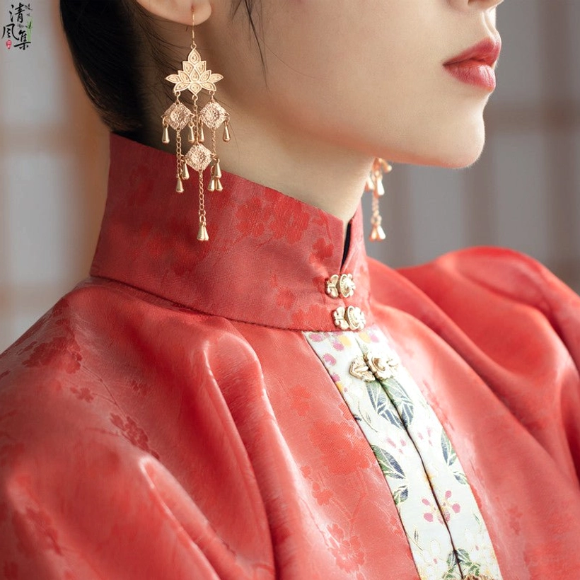 Model wearing antique gold lotus tassel hook Chinese earrings with a red stand collar qipao cheongsam