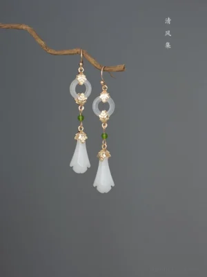 Antique magnolia Chinese earrings for Hanfu displayed on a natural twig with white flower drops jade-look round charms green beads and gold-toned details