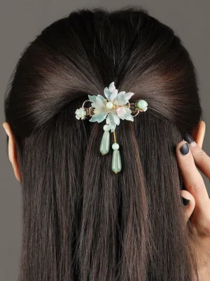 Antique mint floral hanfu hair pin worn at the back of long dark hair with layered resin flower petals, gold-tone frame, mint beads, and dangling teardrop pendants
