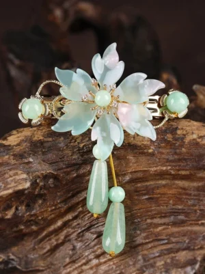 Antique mint green Chinese-style floral hair pin displayed on weathered wood showing layered resin petals, sparkling center, mint beads, and long teardrop pendants
