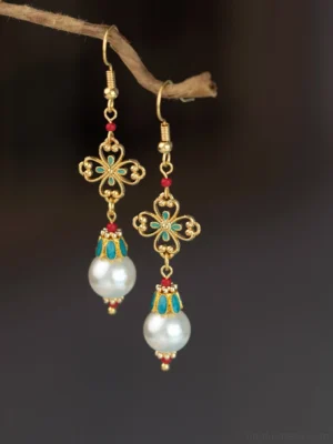 Antique pearl dangle Chinese earrings with gold filigree four leaf charms turquoise accents red beads and white pearl pendants shown in a frontal close up