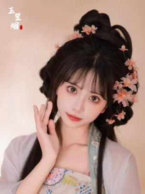 Front view of a woman wearing light pink apricot blossom Hanfu hair pins and floral hair clips with a traditional Chinese coiled hairstyle