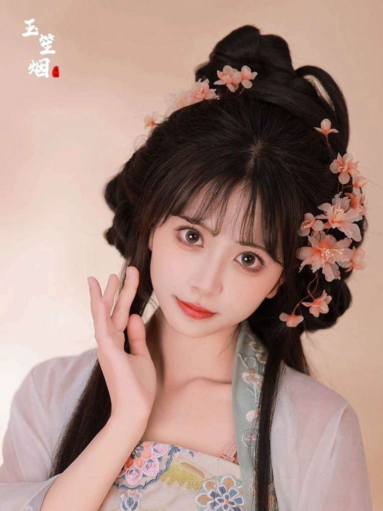 Front view of a woman wearing light pink apricot blossom Hanfu hair pins and floral hair clips with a traditional Chinese coiled hairstyle