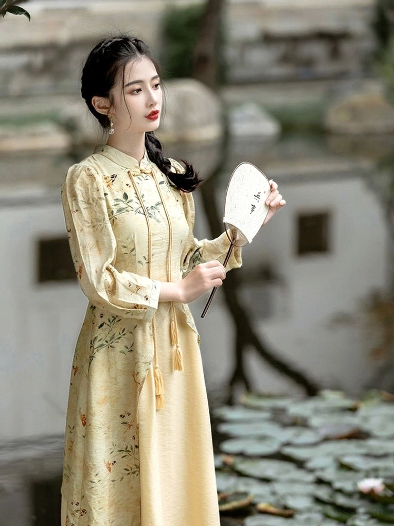 Side view of an apricot beige modern Hanfu cheongsam midi dress with ink floral pattern, puff sleeves, tassel pendants, fitted waist, and flowing A-line skirt