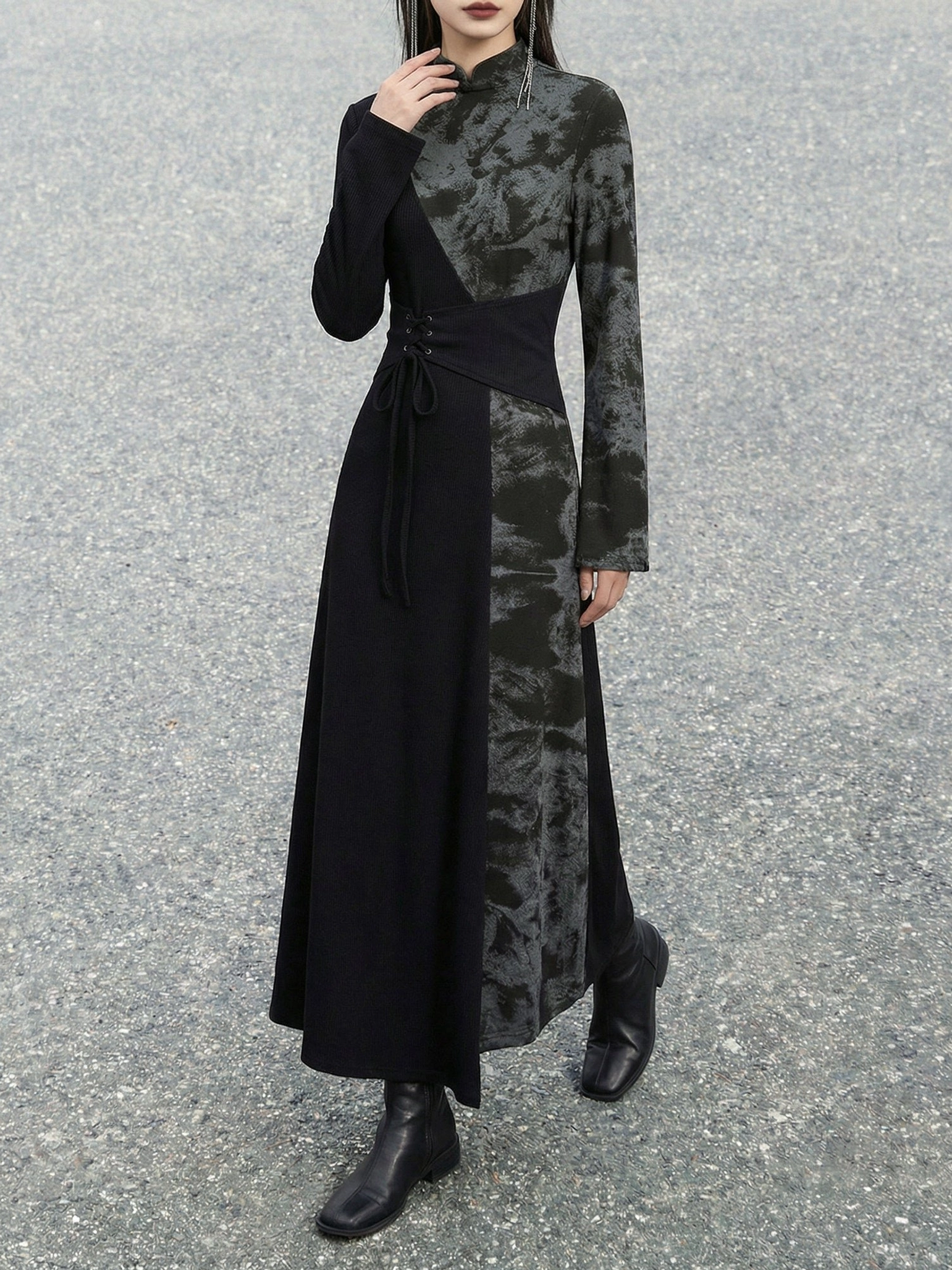 Three-quarter front view of an asymmetric black New Chinese style long sleeve dress with stand collar, patterned fabric panels, and decorative lace-up waist