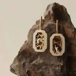 Asymmetrical Chinese cat pavilion stud earrings with gold window lattice, milky white octagonal frames, silver cats and red gemstone accents on stone