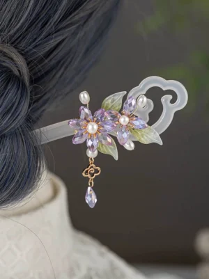Aurora Night Chinese hair stick worn in a Hanfu-inspired hairstyle, featuring purple crystal flowers, faux pearls, green leaves, a cloud-shaped end, and a dangling gold-toned charm