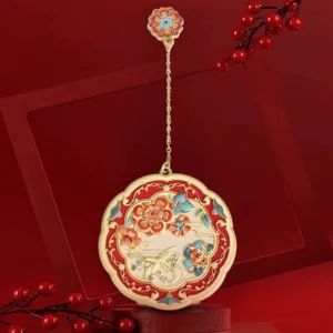 Auspicious Chinese pocket mirror with scalloped round gold-toned frame, colourful floral and bird motifs, red festive background, and matching flower pendant on a delicate chain