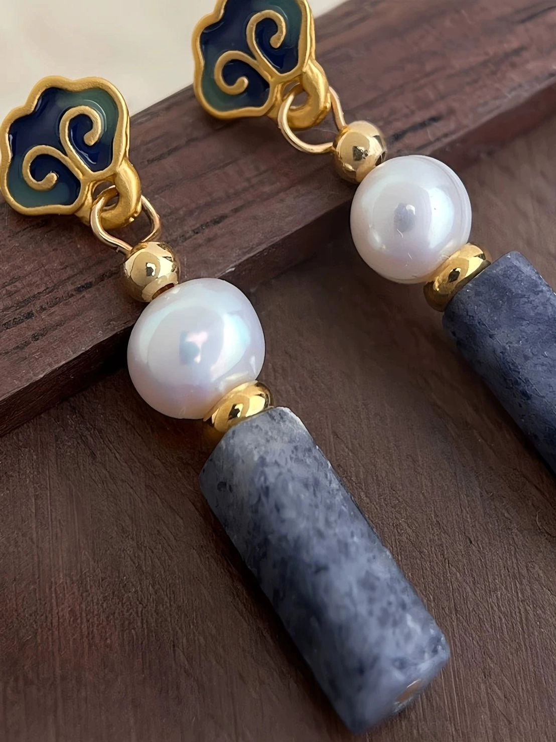 Chinese auspicious cloud earrings worn on the ear with freshwater pearl and gray-blue stone pendants styled with a traditional Chinese blouse and braided hair