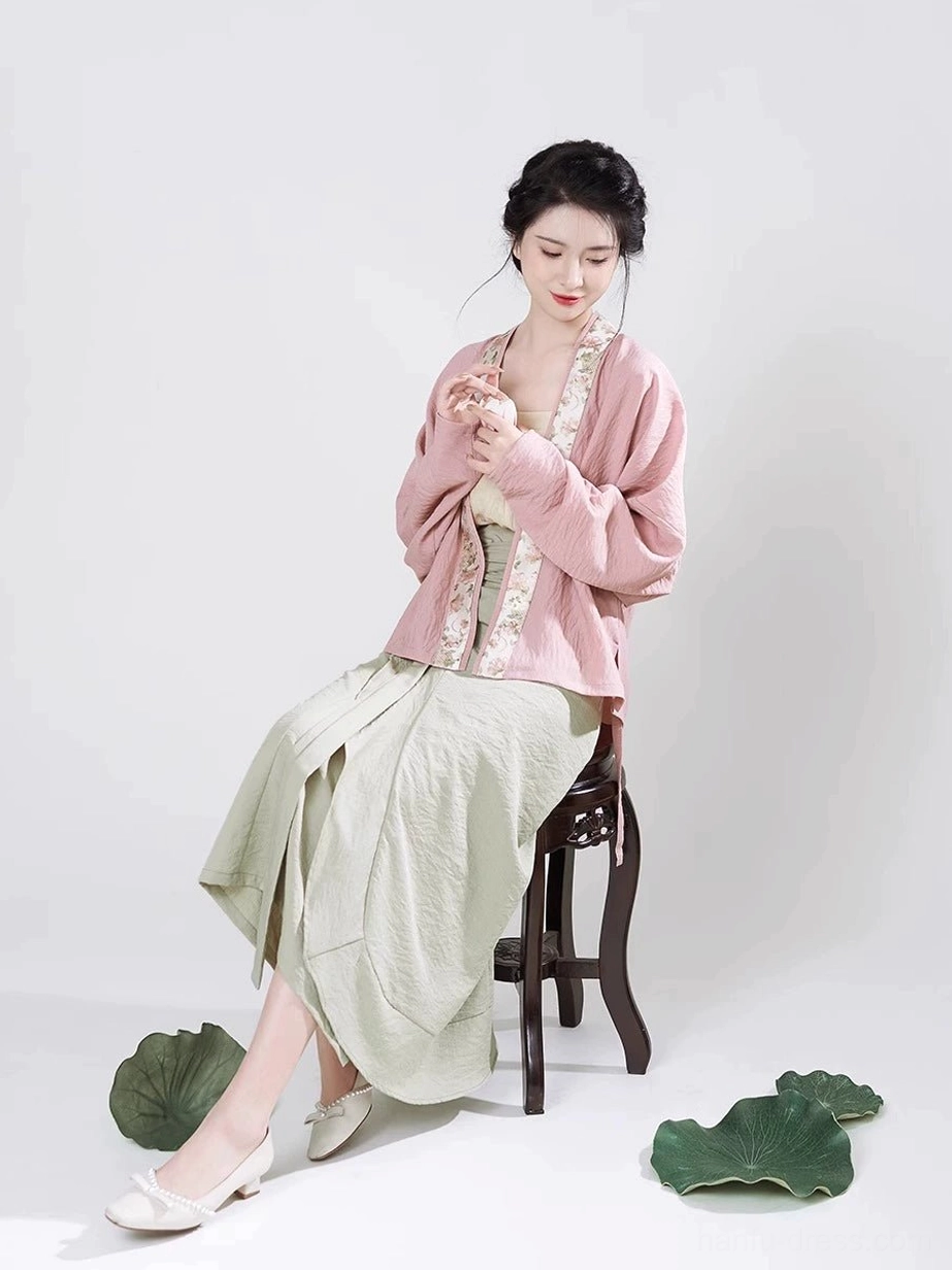 Close seated view of dusty pink winged sleeve Hanfu top with delicate floral trim on cross-collar placket