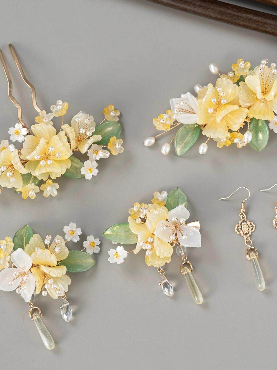 Complete yellow floral Hanfu hair accessories set with white resin flowers green leaves faux pearls gold details and glass drop charms displayed on a neutral studio background