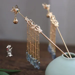 Ayayun Mist butterfly tassel Chinese Hanfu hairpin with gilt-tone openwork details and blue grey waterdrop pendants displayed on a celadon vase