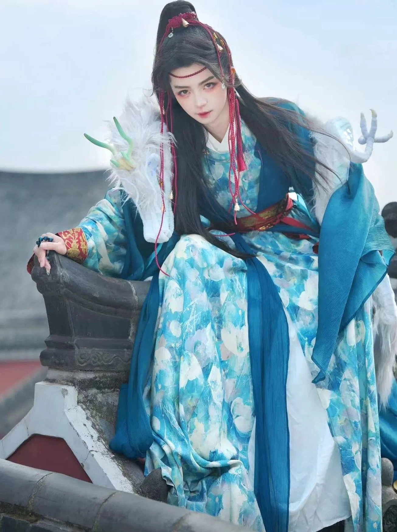 Azure Dragon Chinese fantasy Hanfu costume seated side view showing shoulder cloud collar and white dragon-inspired arm ornament