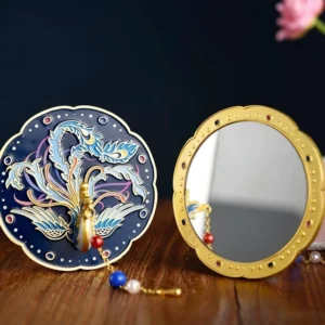 Front and back view of azure Chinese phoenix hand mirror showing reflective makeup mirror surface, gold-tone frame, red gem-like accents, and matching tassel