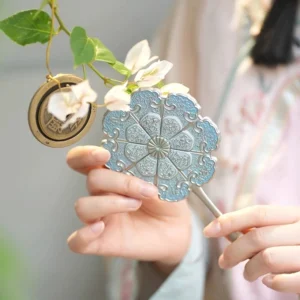Azure lotus relief Chinese hand mirror held by a Hanfu-clad woman, showing the eight-petal blue floral back panel and antique silver handle