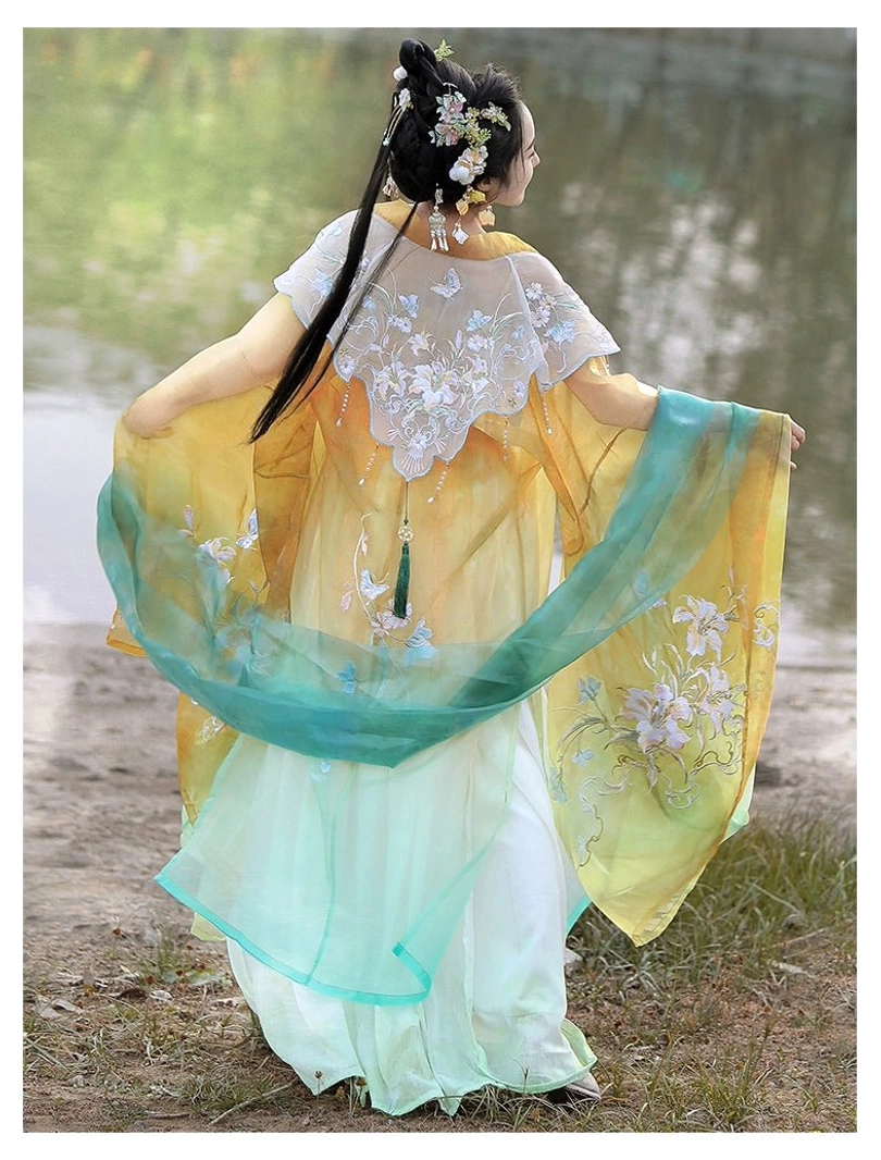 Back three-quarter view of a Tang Dynasty Hanfu dress with white cloud shoulder decoration green embroidered wide sleeves floral skirt and cyan waist details