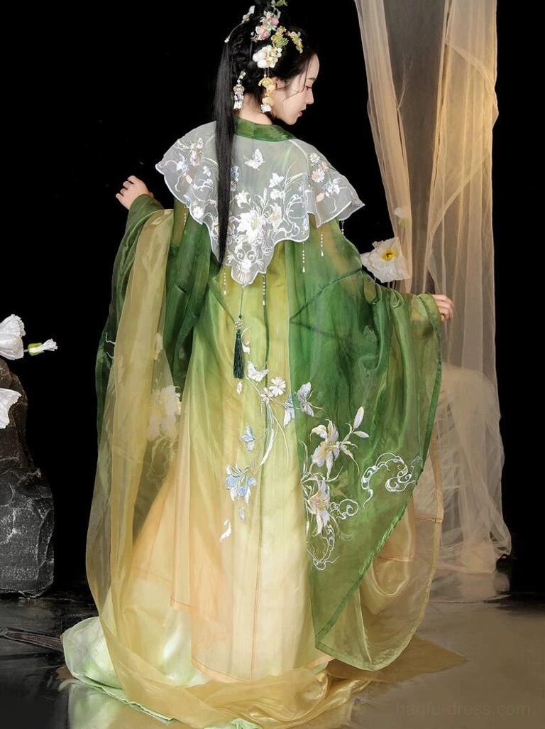 Back view of a Tang Dynasty inspired Hanfu Heziqun dress showing the white cloud lace shoulder detail embroidered green coat and flowing gradient skirt