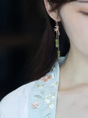 Bamboo design Chinese earrings worn with a light blue embroidered Hanfu collar, showing elegant green bead accents and a graceful long drop silhouette
