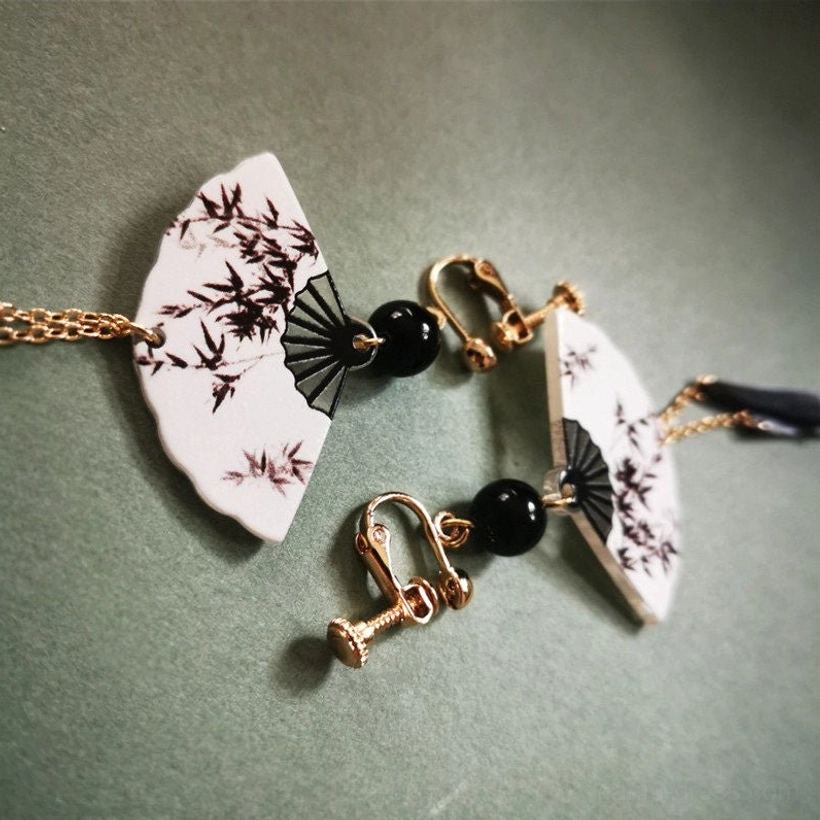 Detailed bamboo fan-shaped Chinese earrings with brown ink artwork, black beads, gold lever-back hooks, and delicate gold chain tassels