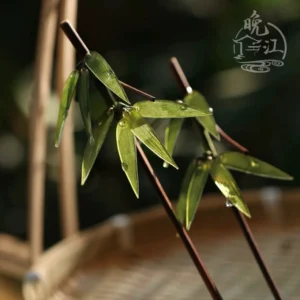 Bamboo leaf Chinese hair stick with green dewdrop details displayed beside a woven bamboo basket