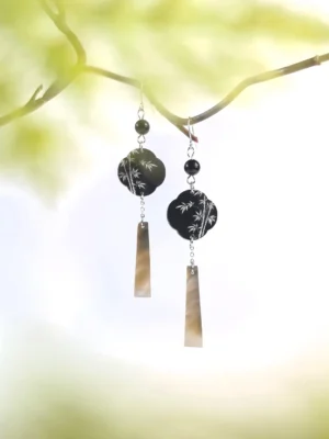 Pair of bamboo leaf Hanfu drop earrings with black bead accents, silver tone components and shimmering tapered shell pendants in warm natural light