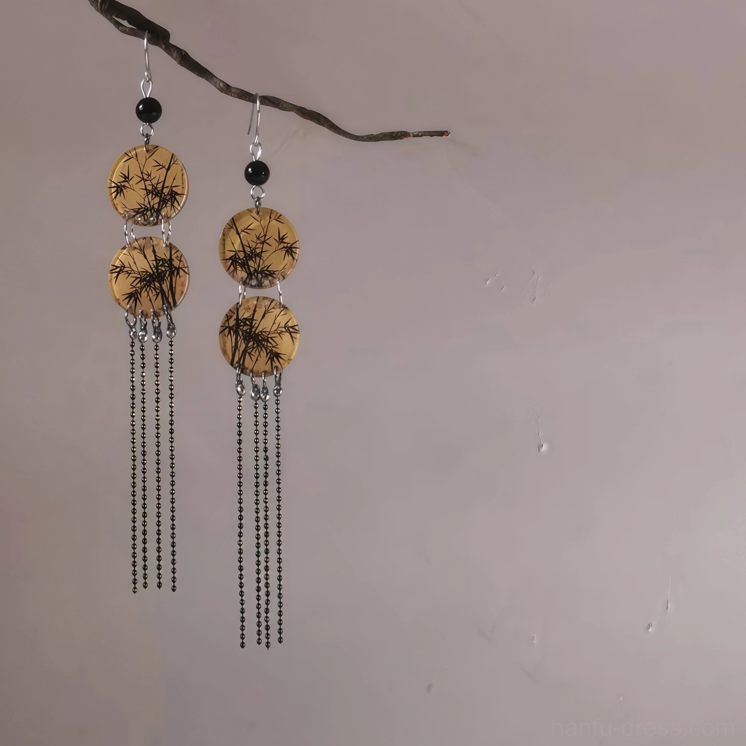 Full front view of symmetrical bamboo leaf round tassel earrings with 925 silver hooks, warm bamboo print discs, black accent beads, and delicate tassel chains