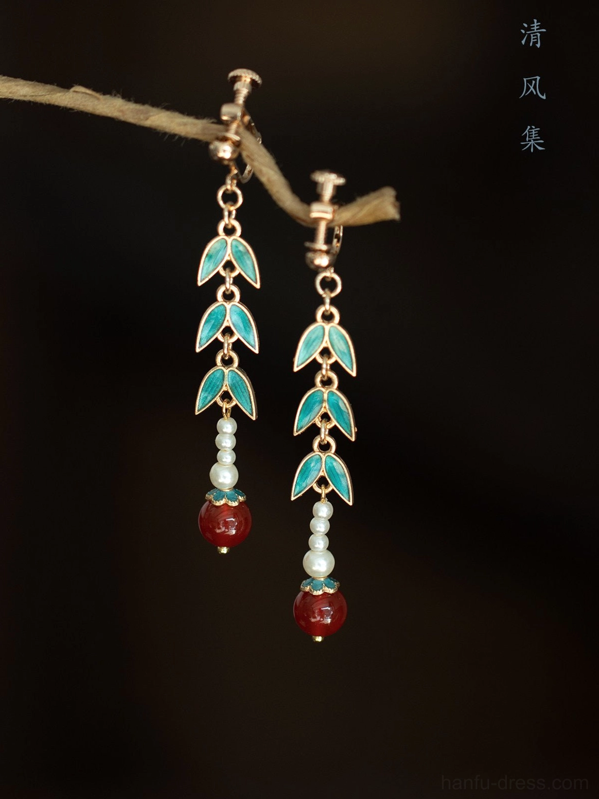 Close-up view of Chinese bamboo drop earrings with blue green enamel leaves pearl beads red pendants and hook ear wires