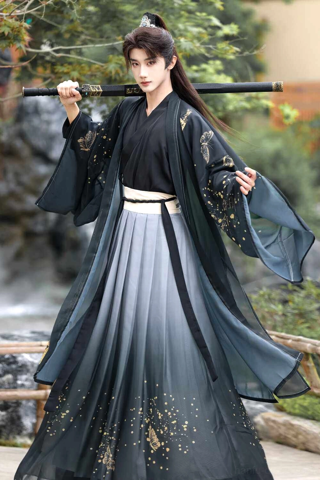 Black men’s wuxia fantasy hanfu full set with sword over shoulder, wide flowing outer robe, white waist seal, ink gradient layers, and gold speckles