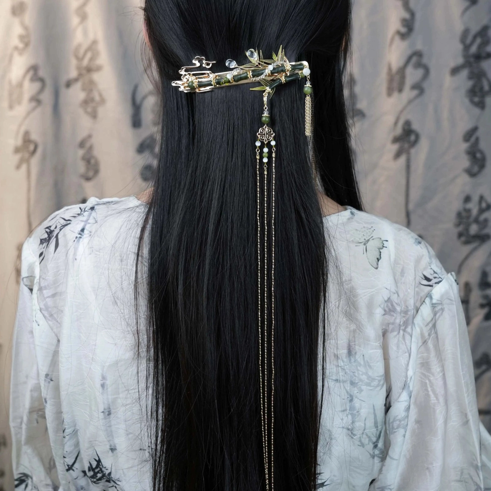 Bamboo tassel Chinese Hanfu back hair pin with green accents and crystal-like details worn on long black hair with an ink painting style Hanfu outfit