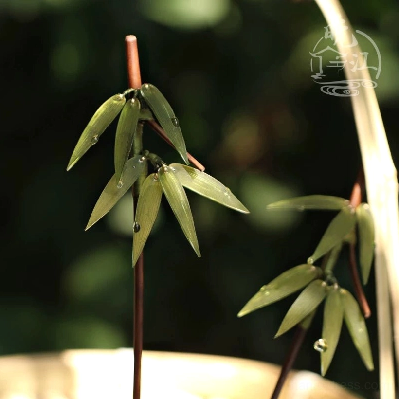Two bamboo themed Chinese hair sticks outdoors showing dark shafts and green leaf dewdrop ornaments