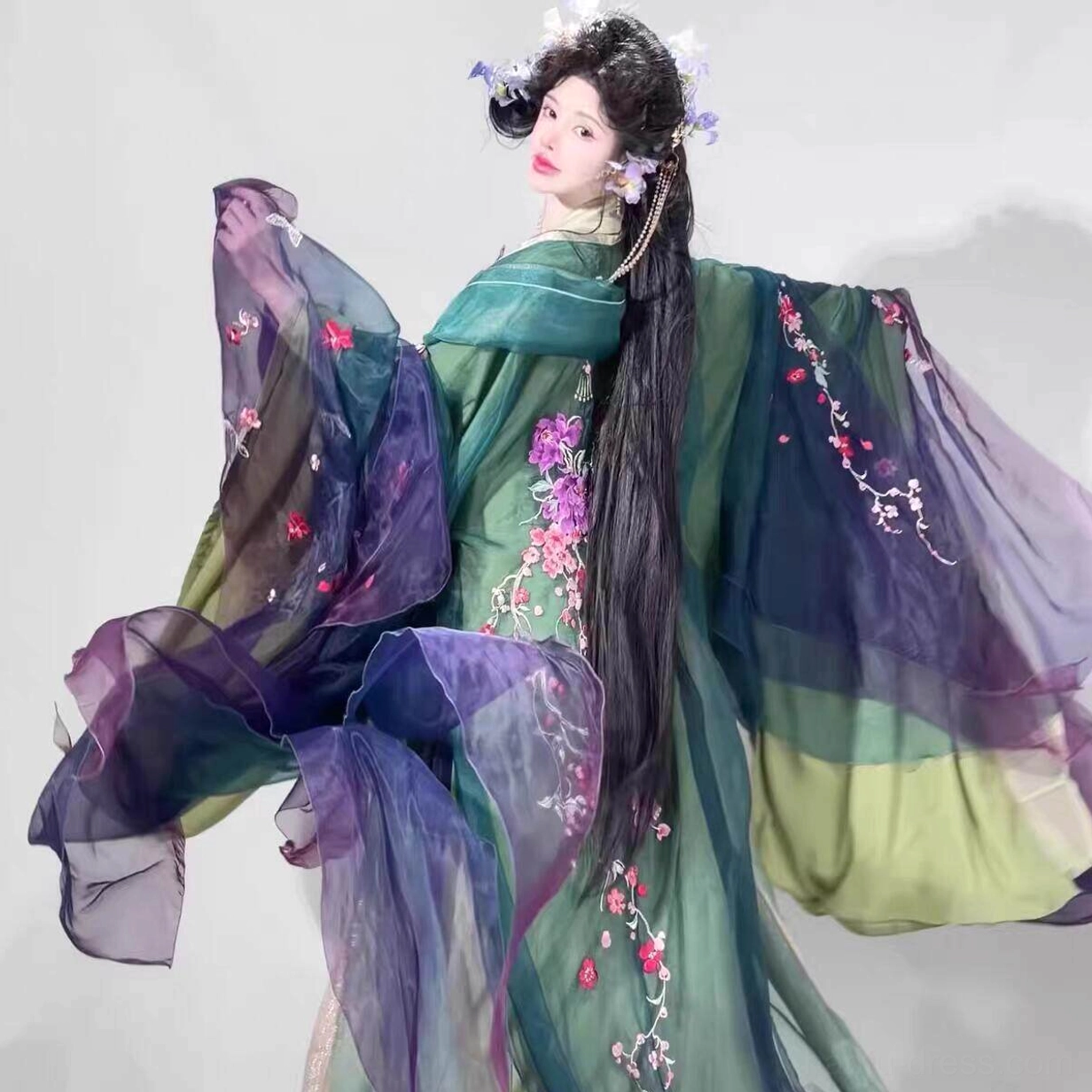 Back side view of Begonia Still Blooming Chinese hanfu costume with embroidered green robe, purple layers, and dramatic flowing sleeves