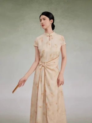 Beige floral cheongsam dress side front view showing gathered twisted waist and flowing asymmetrical maxi hem