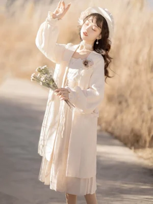 Side three-quarter view of beige modern Hanfu style Lolita dress and long cardigan with square neckline, sheer layered skirt, and floral brooch