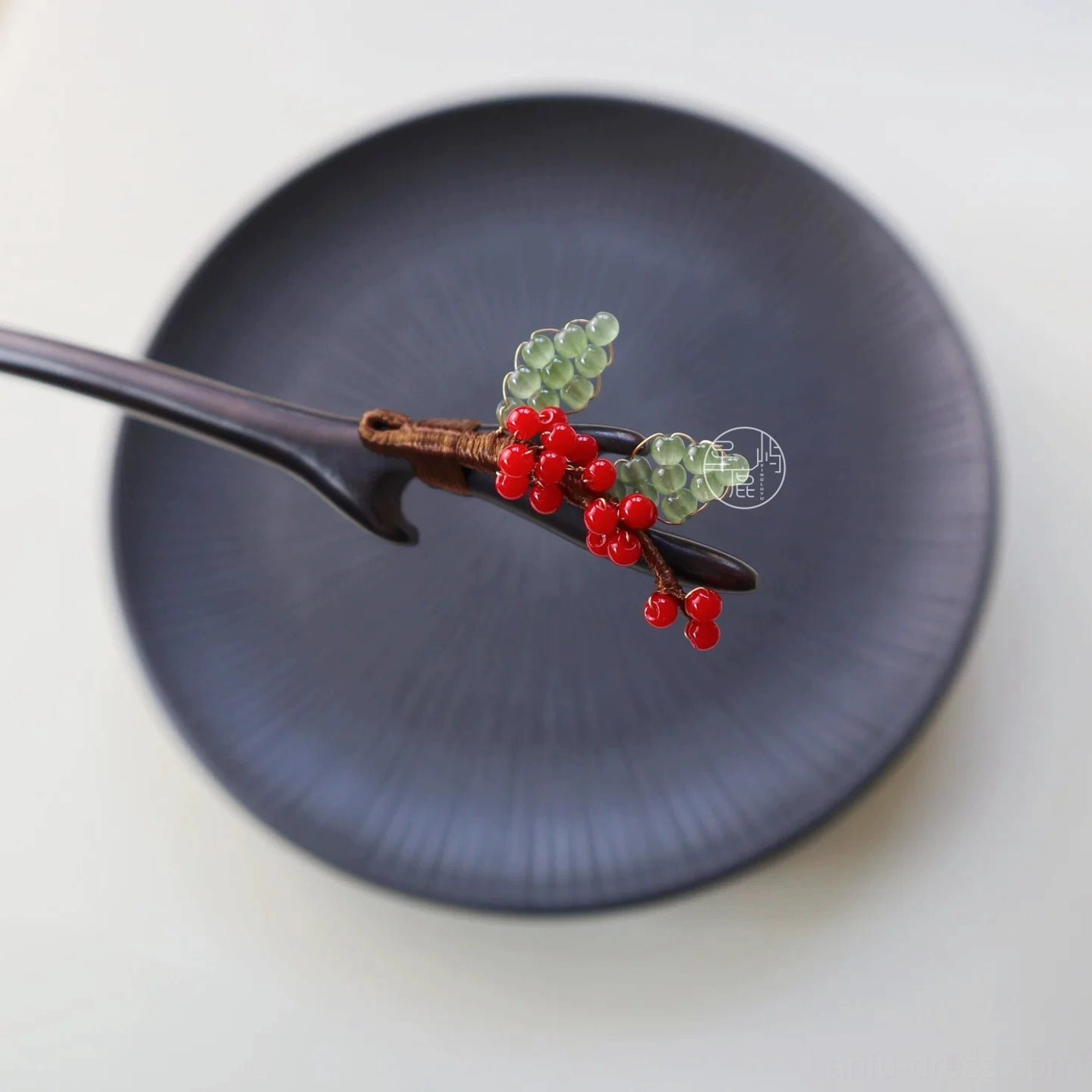Berry-themed handmade Hanfu hair accessory stick shown on a dark blue ceramic dish with branch-shaped wood and delicate red and green floral bead details