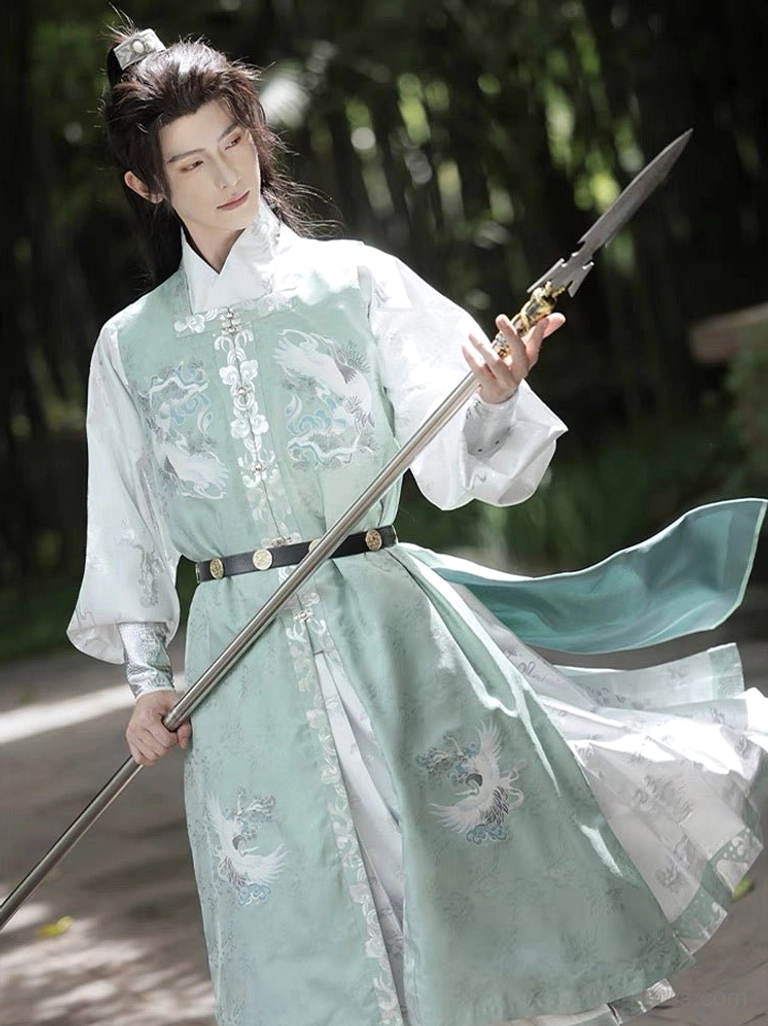 Male model wearing Bixiao jade green Ming Dynasty wuxia hanfu with crane motifs while holding a spear in a bamboo forest