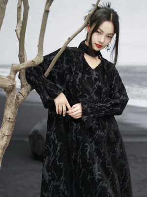 Black chenille jacquard modern Hanfu loose maxi dress with V-neck halter sash, flared sleeves, and relaxed silhouette shown on a model at a black sand beach