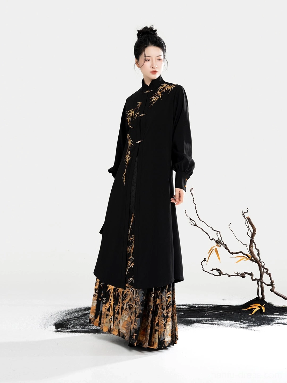 Flat lay of a black Chinese blouse featuring a stand collar lantern sleeves metal toggles and golden bamboo decoration