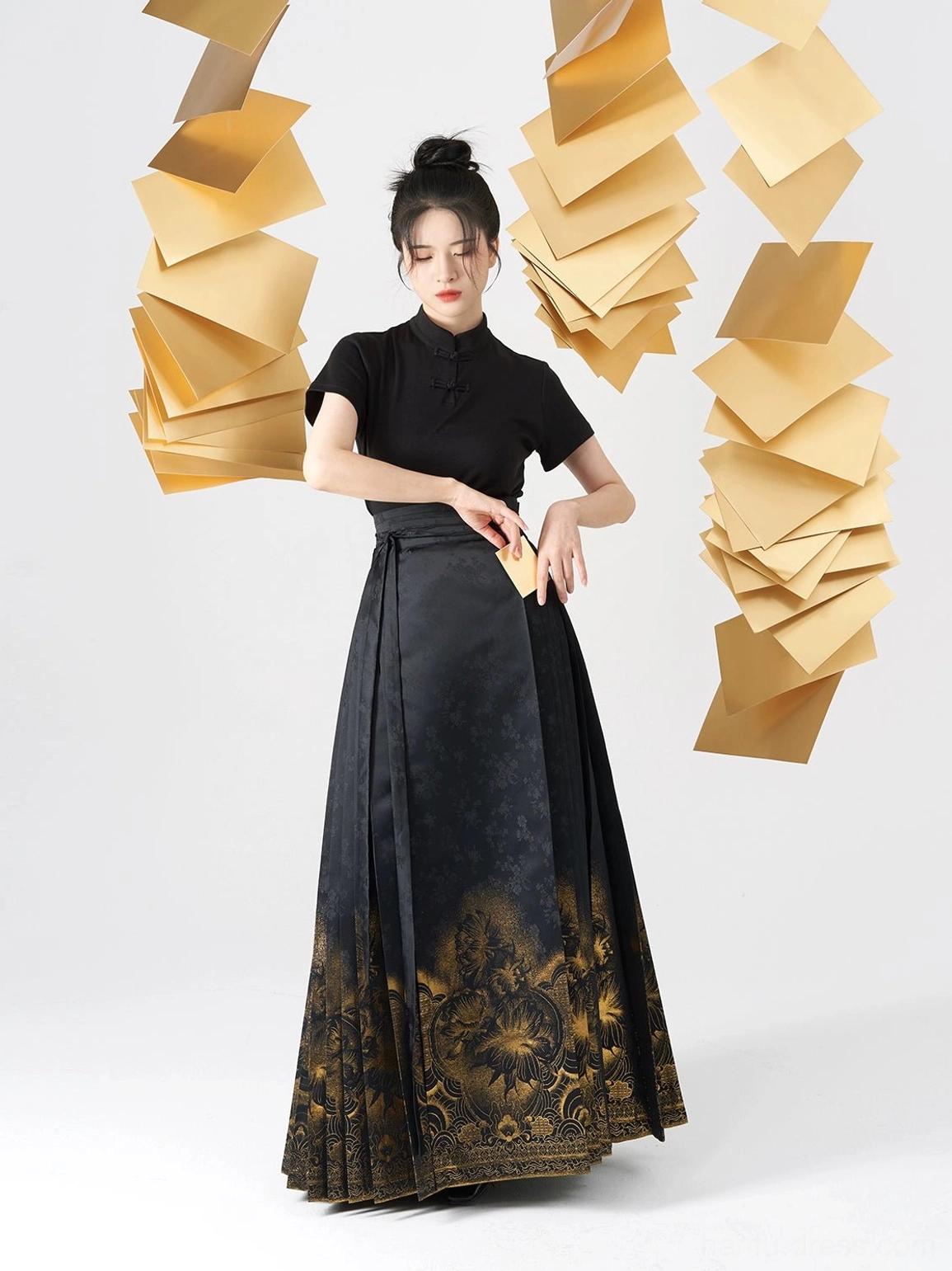 Front view of a black Chinese Hanfu two-piece outfit with fitted stand-collar top and golden floral pleated skirt hem