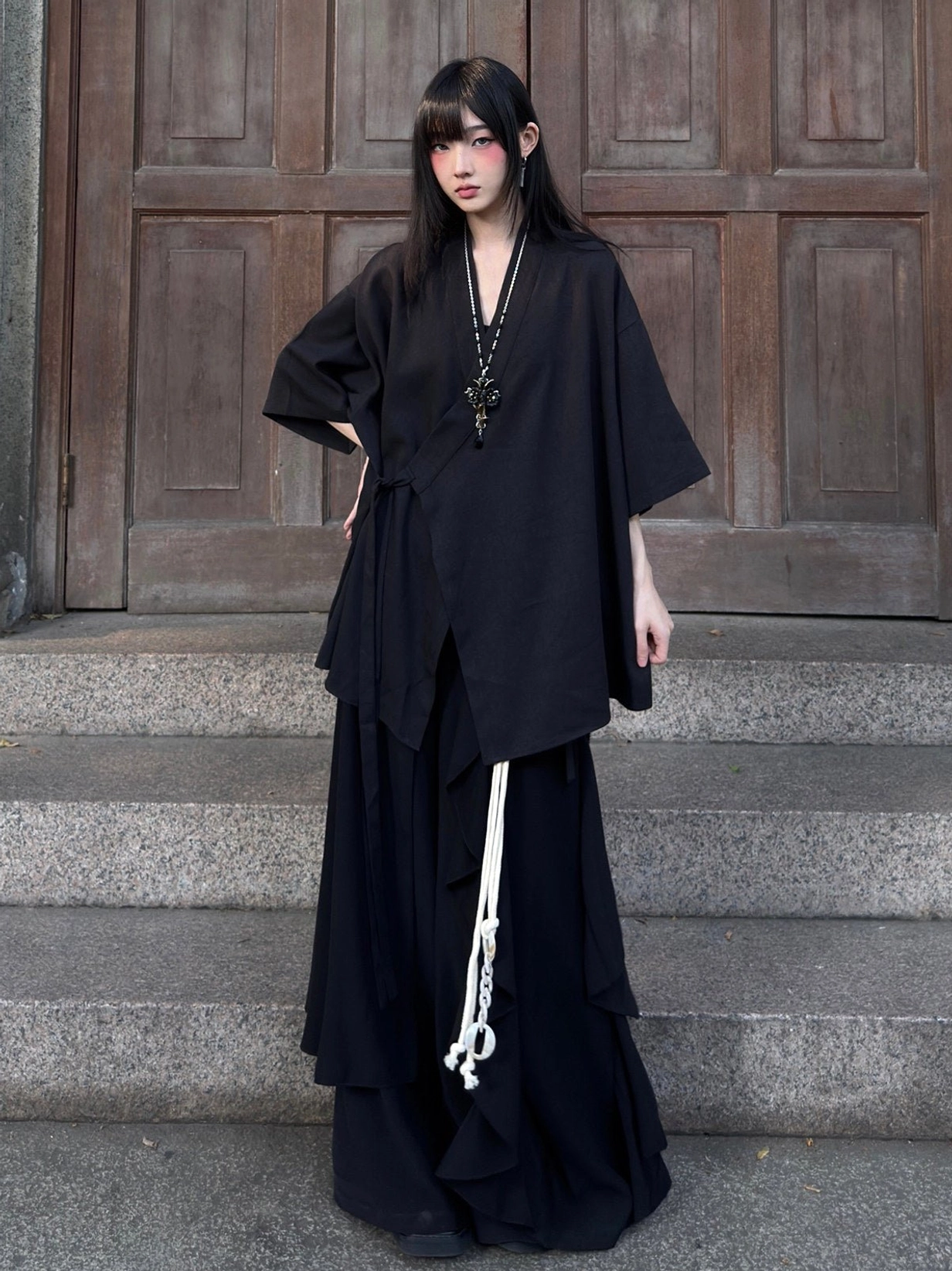 Low-angle full-body view of a black Chinese-inspired modern Hanfu cardigan with oversized fit and classic cross collar