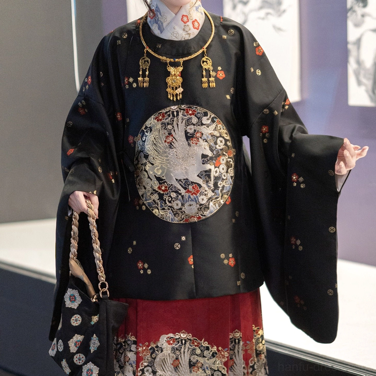 Close-up of black Chinese New Year Hanfu round-collar top with silver crane medallion and traditional necklace